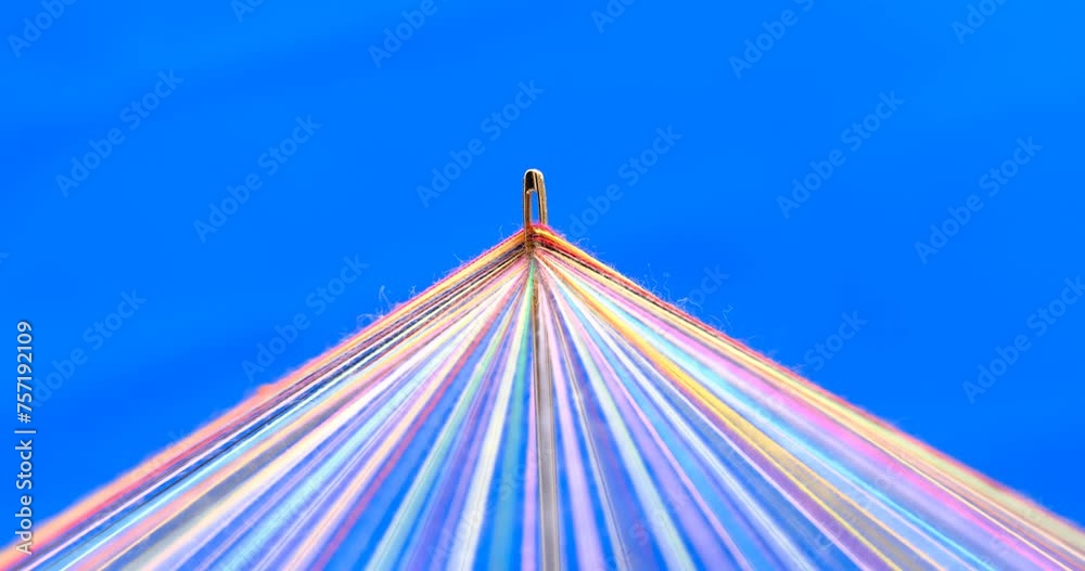 Converging Multi-colored Sewing Thread on a rotating table, blue background
