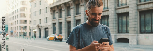 Young man with beard walks down the street using cellphone, Panorama