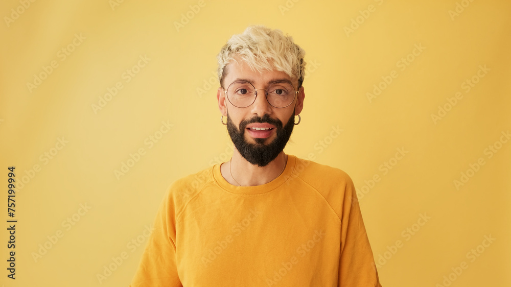 Guy with glasses, dressed in yellow T-shirt looking at camera with big eyes, says wow, isolated on yellow background in studio Guy with glasses, dressed in yellow T-shirt looking at camera with big eyes, says wow, isolated on yellow background in studio