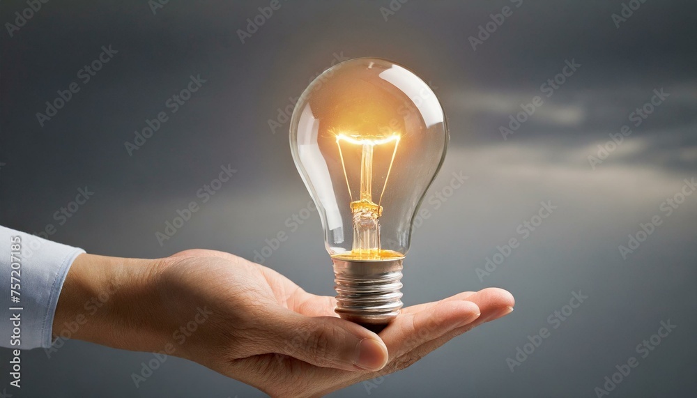 A hand holding a glowing light bulb