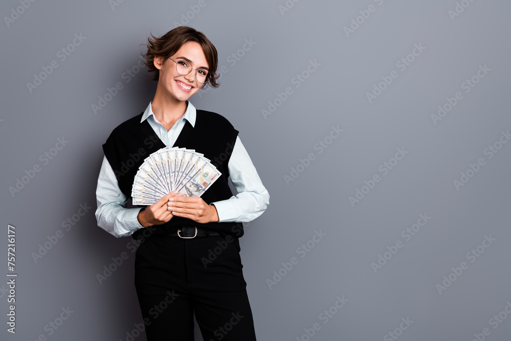 Photo of gorgeous cheerful lady wear stylish black clothes hold money advertising credit bank isolated on gray color background Photo of gorgeous cheerful lady wear stylish black clothes hold money advertising credit bank isolated on gray color background