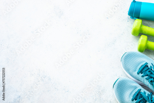 Fitness background, flat lay image. Sneakers, dumbbells and bottle of water. Training, workout and fitness concept.