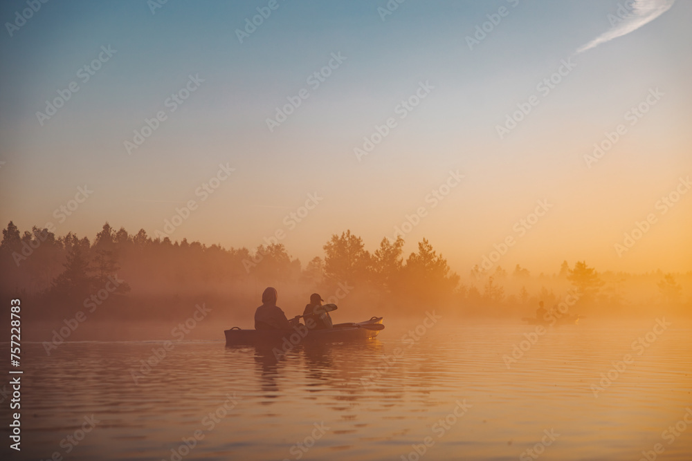 silhouette of two people kayaking in river on sunrise