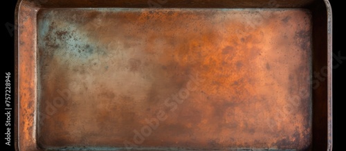 A closeup of a weathered baking tray with rust on a black background, showcasing a mix of brown hues and amber tints resembling a hardwood flooring pattern