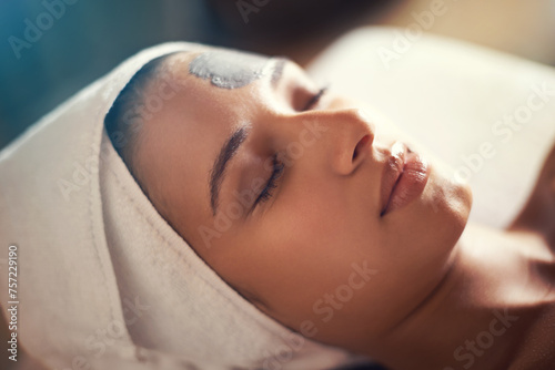 Woman, relax and wellness in spa for clay mask, therapy and cosmetic treatment with eyes closed for break and skincare. Young person with towel on head for peace, holistic and hygiene care for beauty