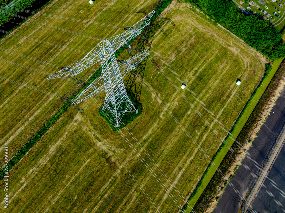 Aerial view of a towering electric pylon amidst green fields Aerial view of a towering electric pylon amidst green fields