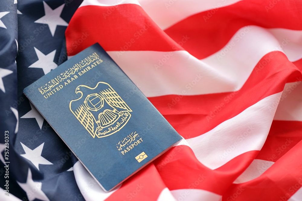 Fototapeta premium Blue United Arab Emirates passport on United States national flag background close up. Tourism and diplomacy concept