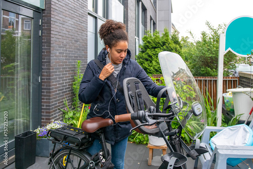Young woman adjusting her scarf before a ride on her motorcycle in urban setting photo