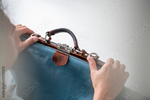 Hands clasping a stylish suede handbag. photo