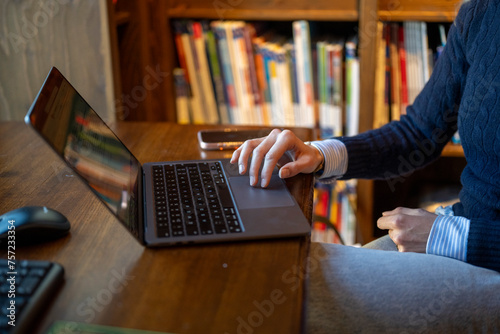 Person working on a laptop in a cozy home office. photo