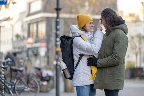 Two friends share a warm moment on a chilly city street. photo
