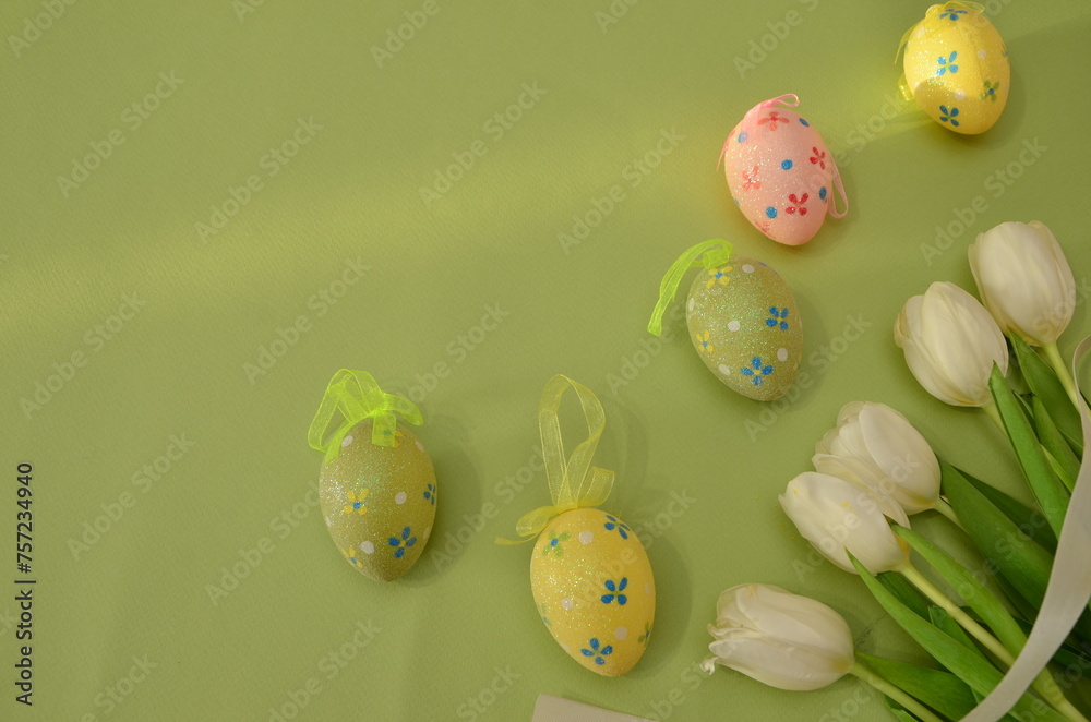 Easter, Easter egg color is bright, spring Orthodox holiday. colorful decorated eggs on a green background. Happy Easter, white tulips. gift box tied with ribbon