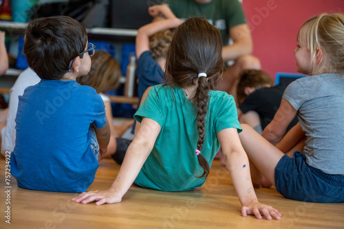 Children sitting attentively on the floor during a group activity. photo