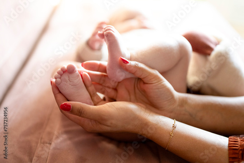 A tender moment as a mother cradles her baby's feet in her hands. photo