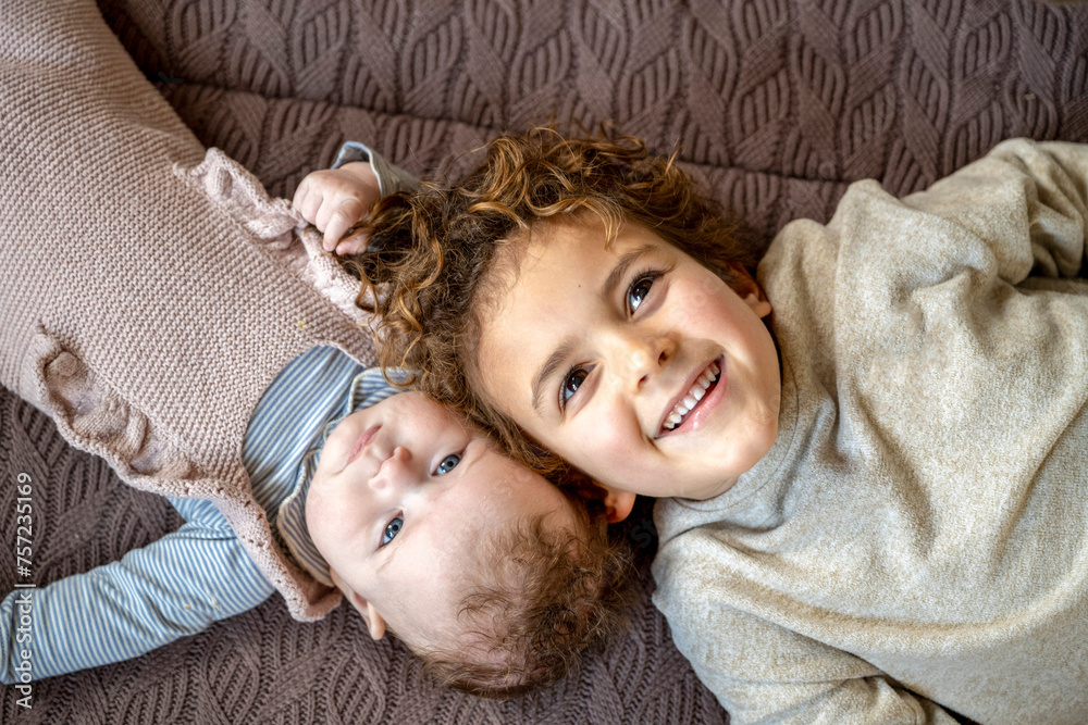 Two siblings sharing a playful moment on a cozy quilt. Two siblings sharing a playful moment on a cozy quilt.
