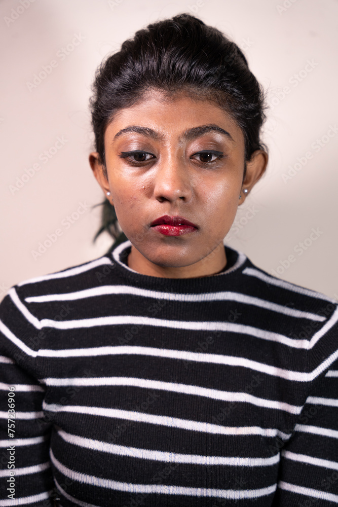 Fototapeta premium A woman with black and white stripes on her shirt is looking at the camera. She has red lipstick on and her eyes are closed