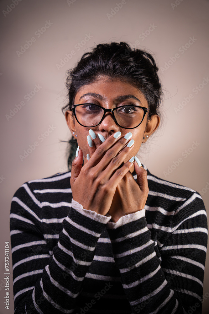 A woman with long hair and glasses is standing in front of a wall. She is holding her hands together and has a blue nail polish on her nails A woman with long hair and glasses is standing in front of a wall. She is holding her hands together and has a blue nail polish on her nails
