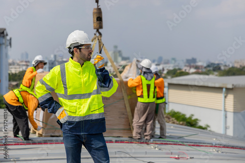 Technicians Install photovoltaic solar modules on roof of factory. Engineers install or fix solar cells in roof of factory. Technician worker on solar panels.  photo