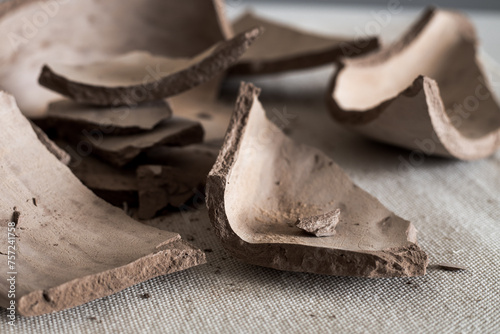 A broken clay vase in close-up. Fragments of a ceramic vase on the table. Clay broken shards in close-up. Side view. photo