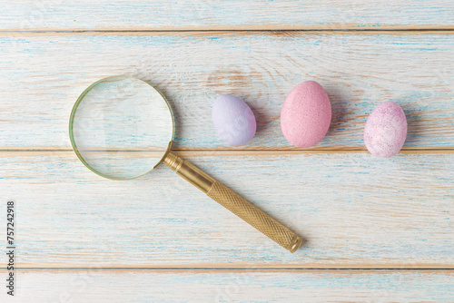Magnifying Glass and Colorful Eggs on Wooden Surface