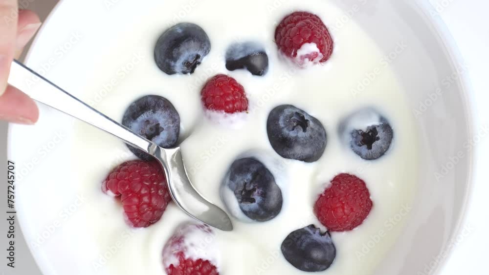 Greek yogurt with raspberry and blueberry scooped withs poon from a Bowl, close up, top view Greek yogurt with raspberry and blueberry scooped withs poon from a Bowl, close up, top view