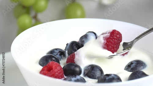 Greek yogurt with raspberry and blueberry scooped withs poon from a bowl, close up photo