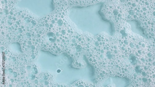 Bubbles of white soap foam on a blue background. Bathtup Soap Foam. Texture of Soap Foam Bubbles. Natural White Shampoo Bubbles Motion. High quality 4k footage