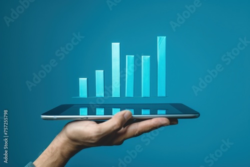 Hand holding a tablet with a bar graph coming out of the screen, business, technology and data analysis concept.