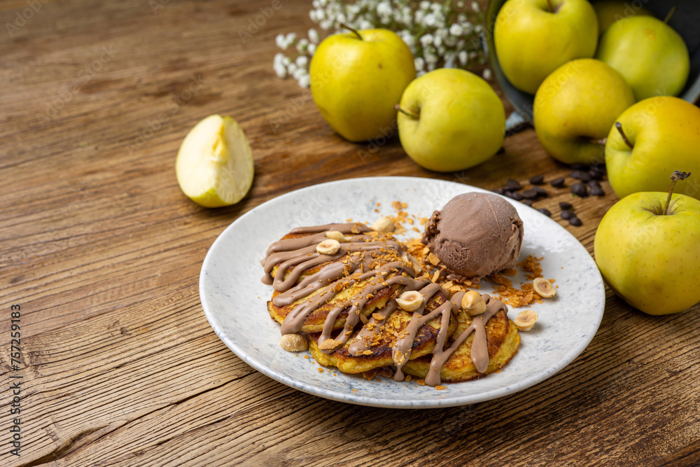 Pancakes with apples, ice cream and nuts on wooden background