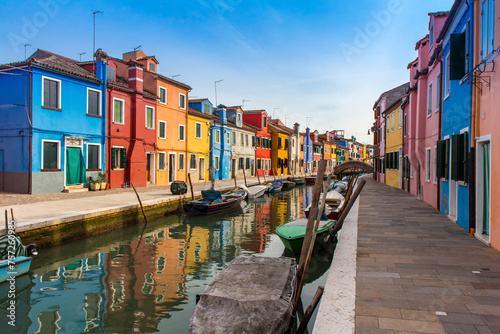 February, 2016 Burano island with colorful houses and buildings on embankment of narrow water canal with fishing boats and view of Venetian Lagoon, Province of Venice, Veneto Region, Northern Italy. B