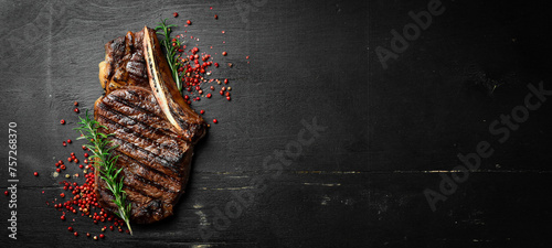 Steak on the bone. tomahawk steak On a black wooden background. Top view. Free copy space.