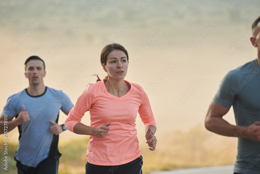 A group of friends, athletes, and joggers embrace the early morning hours as they run through the misty dawn, energized by the rising sun and surrounded by the tranquil beauty of nature A group of friends, athletes, and joggers embrace the early morning hours as they run through the misty dawn, energized by the rising sun and surrounded by the tranquil beauty of nature
