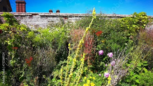 Old walled garden with borders and plants and flowers. English Stately home Warwickshire England UK.