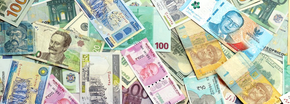 Many banknotes of different currency. Background of big amount of random money bills close up