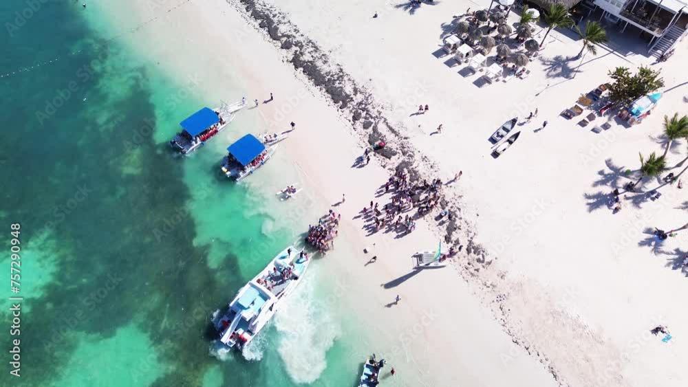 People board a tourist catamaran to embark on a tour of tropical islands with exotic beaches and turquoise lagoon, Dominican Republic, Caribbean Sea. A bird's eye view. People board a tourist catamaran to embark on a tour of tropical islands with exotic beaches and turquoise lagoon, Dominican Republic, Caribbean Sea. A bird's eye view.