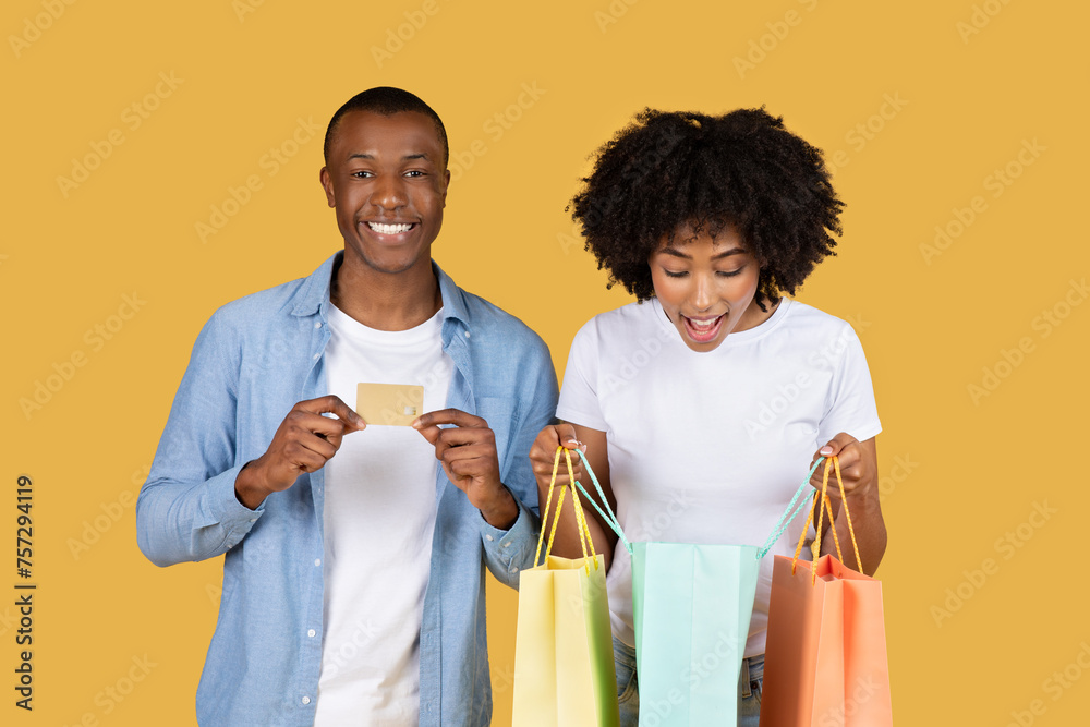 Excited African American couple with colorful shopping bags and a credit card - obrazy, fototapety, plakaty 