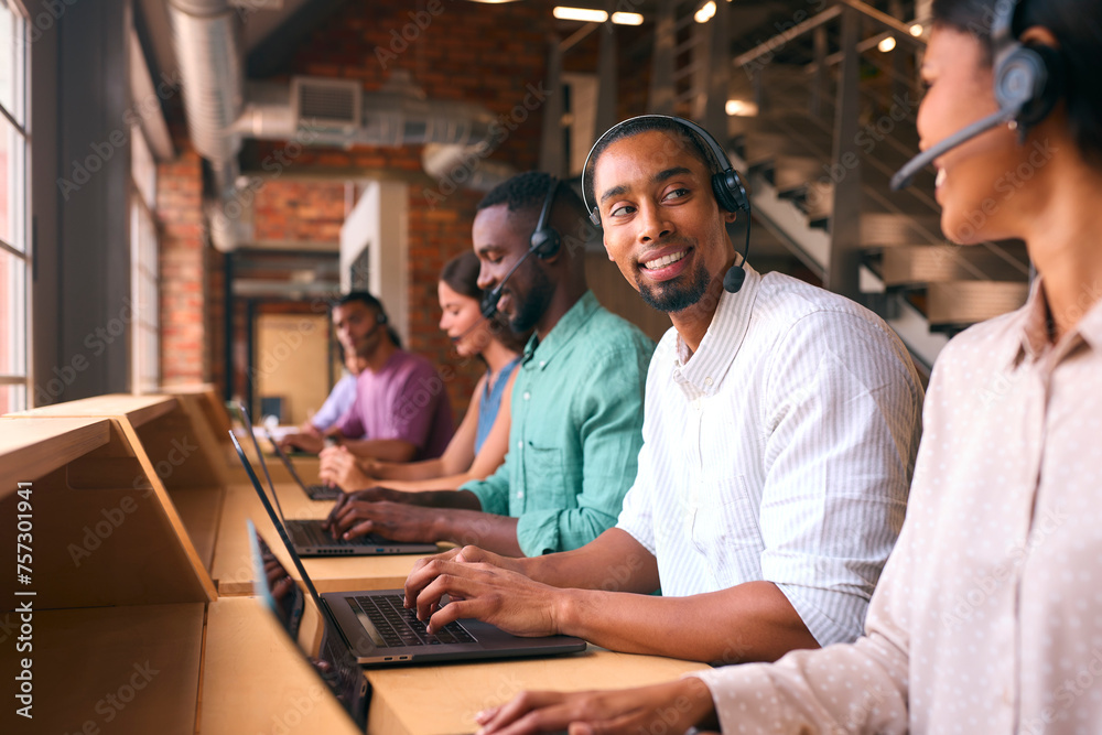 Multi-Cultural Customer Support Or Telesales Team In Modern Open Plan Office Wearing Headsets