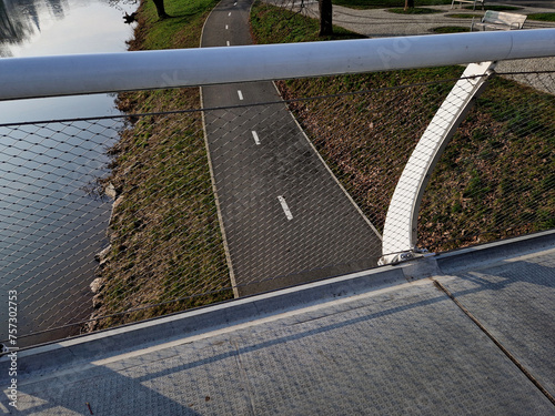 stainless steel mesh stretched on bridge railing.lower steel rope serves as barrier to water drain. the wheelchair user does not have to crash, bike is guided by a cable on side, path, road marking photo