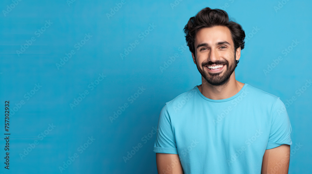 Handsome young man smiling while standing against blue background Handsome young man smiling while standing against blue background