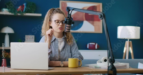 Blogger, content creator, radio host leading morning program. Female wearing glasses and talking in microphone. Woman radio presenter leading morning show. Radio host using table microphone. photo