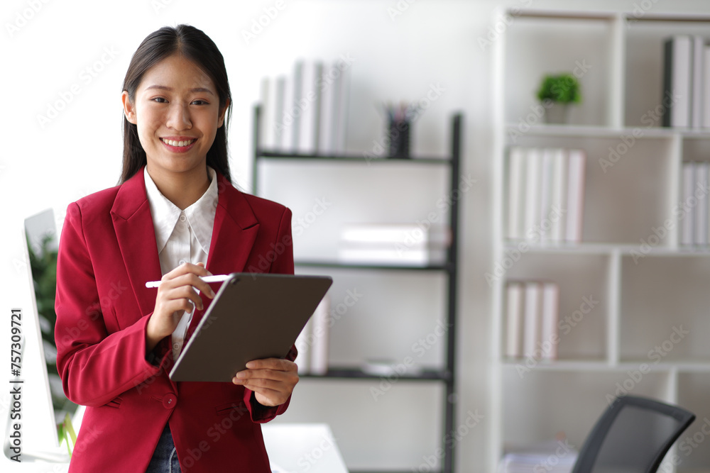 Portrait of attractive Asian businesswoman standing holding tablet in office. Portrait of attractive Asian businesswoman standing holding tablet in office.