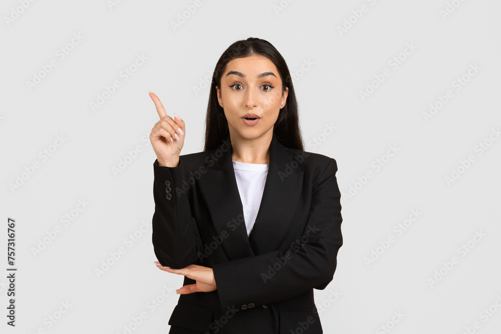 Surprised businesswoman pointing up, having idea Surprised businesswoman pointing up, having idea