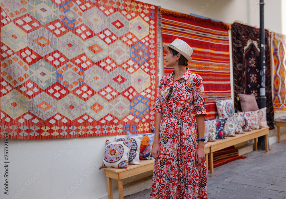 Obraz premium female summer travel to Antalya, Turkey. young asian woman in red dress walk through old town Kalechi , female tourist traveler discover interesting places and popular tourist traditional carpet
