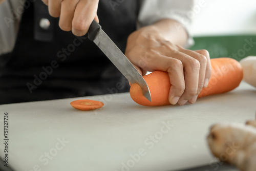 Close-up of a young woman's hands cutting carrots and preparing them for cooking. Vegetables contain many vitamins and are beneficial to the health of the body. .