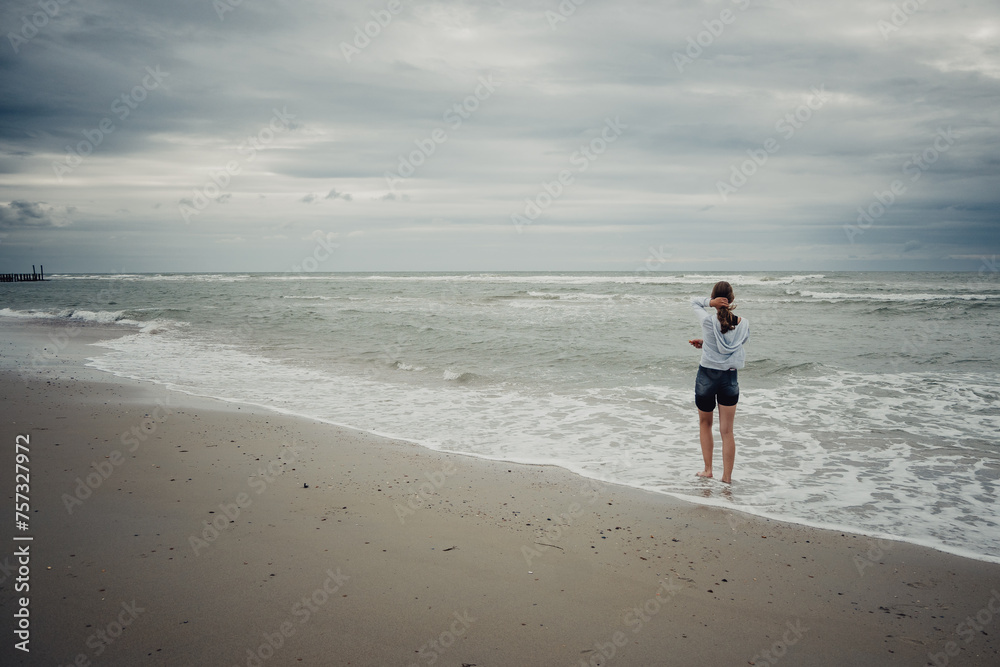 Mädchen schaut am Strand bei Domburg auf das Meer hinaus