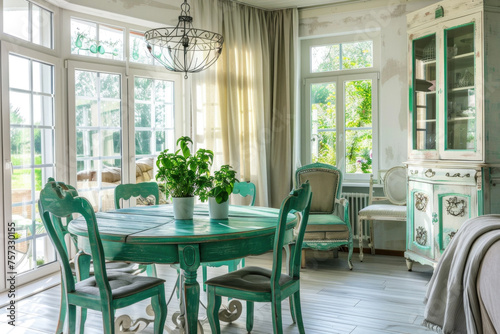 Rustic  vintage furniture  table and chairs of various bright colors in the dining room with large windows.