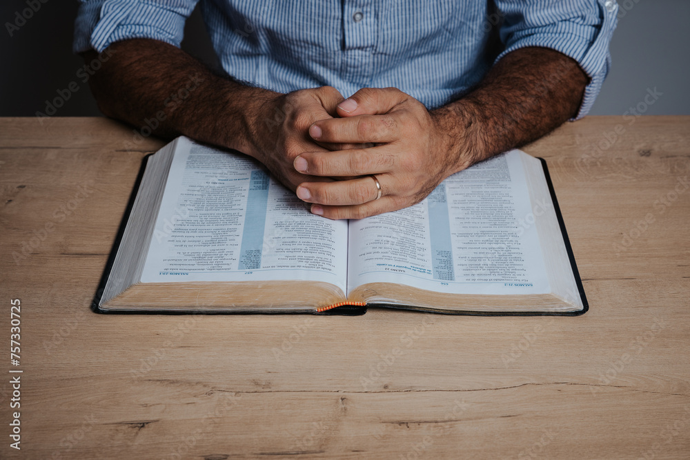 Naklejka premium Hands of a Man praying over a bible