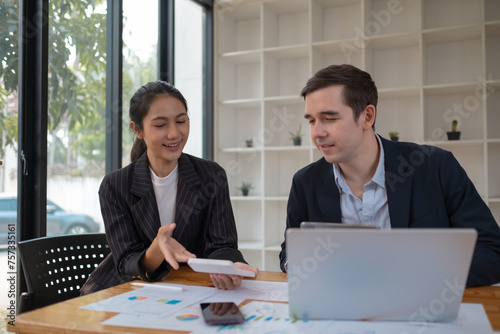 Two business people using a laptop ipad togerher in an office, a man and a women analyzing documents stat at office photo