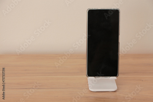 smart phone in phone holder. mobile phone with phone stand holder on the desk. photo