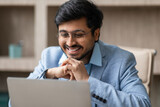 Hindu professional businessman wearing eyeglasses looking at laptop in office
